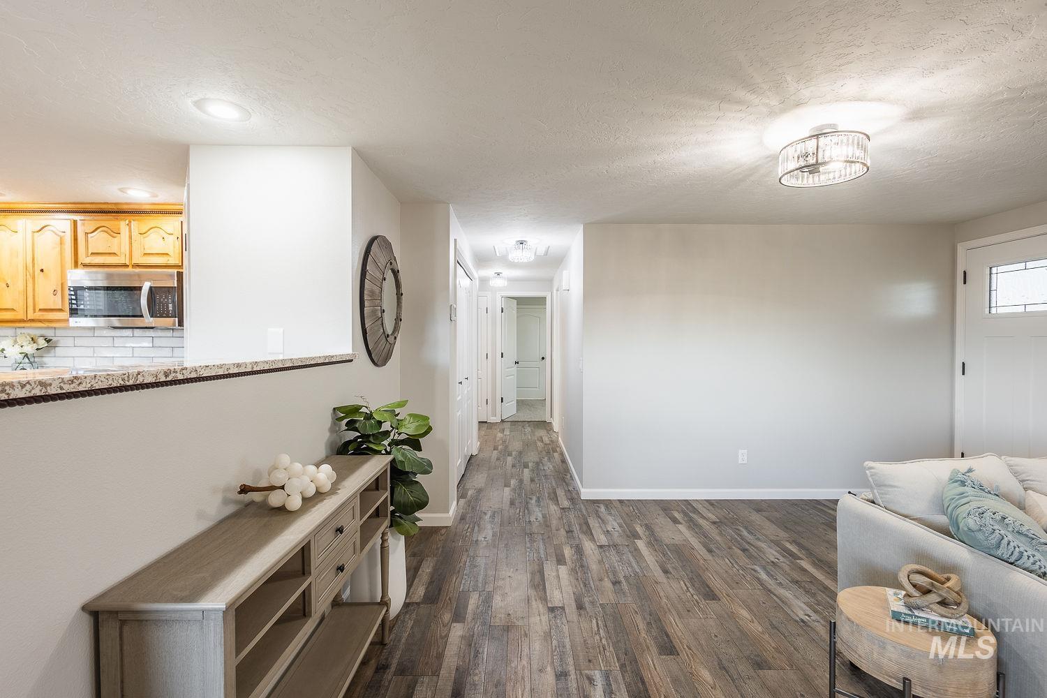 Corridor featuring a textured ceiling and dark wood-style flooring