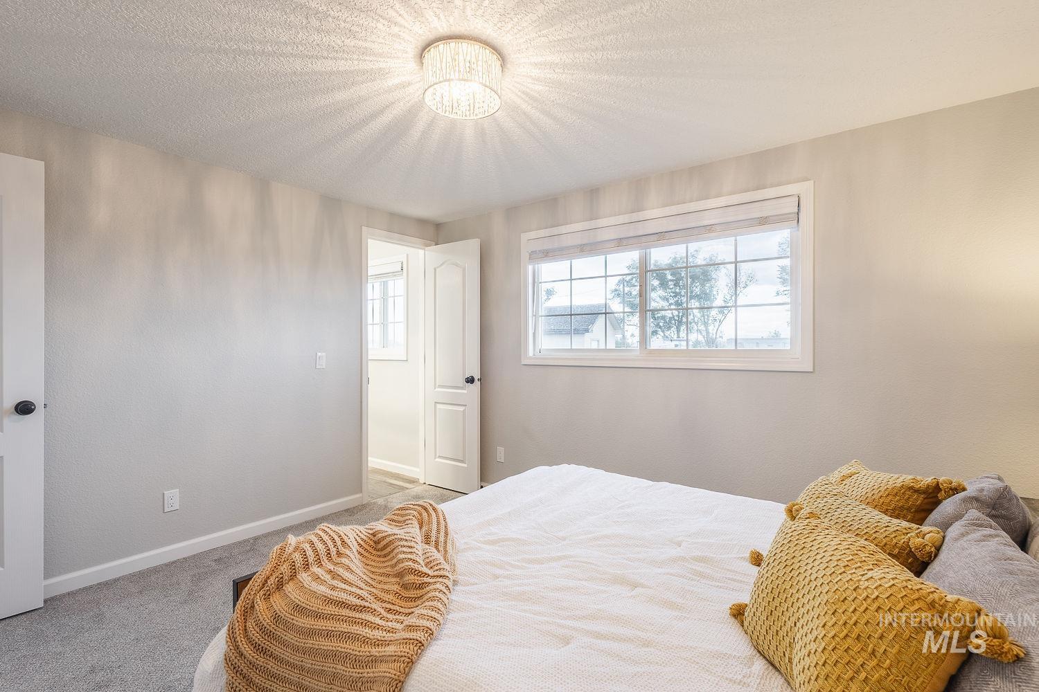 Bedroom featuring light colored carpet, a textured ceiling, and a chandelier