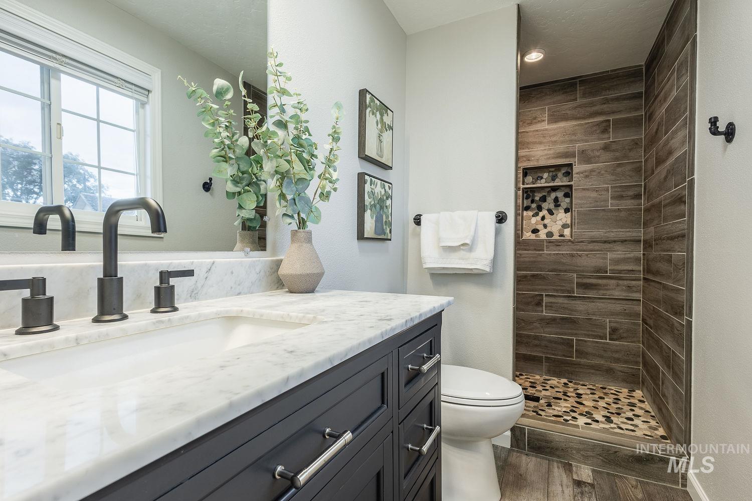 Bathroom featuring vanity, dark wood-type flooring, and tiled shower