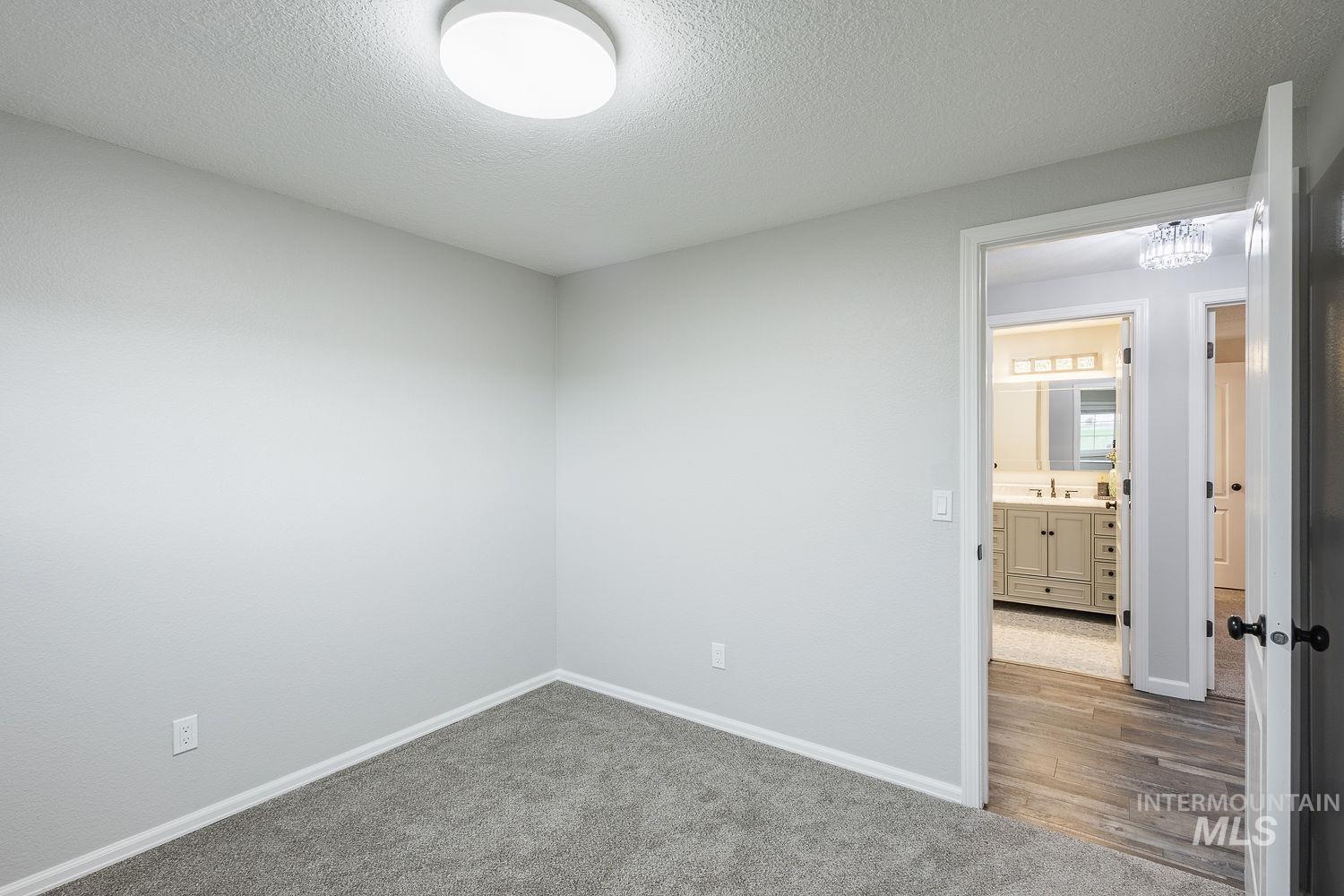 Carpeted empty room featuring a textured ceiling and baseboards