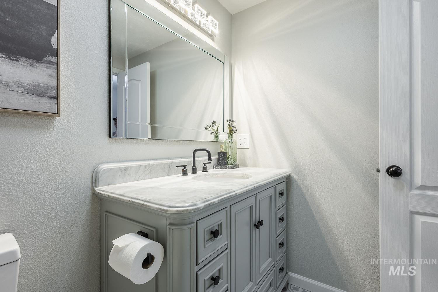 Bathroom featuring a textured wall and vanity