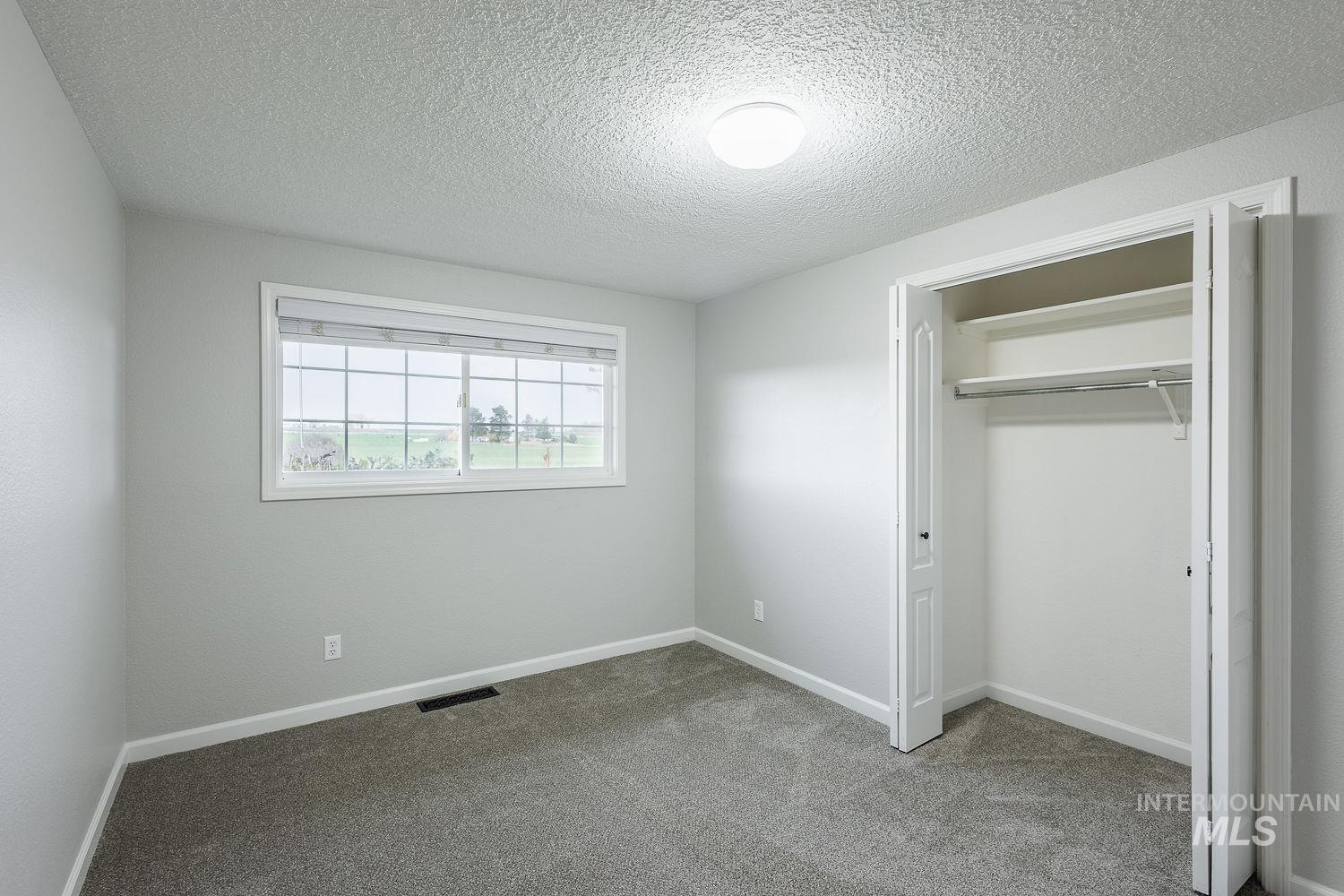 Unfurnished bedroom with light carpet, a textured ceiling, and a closet
