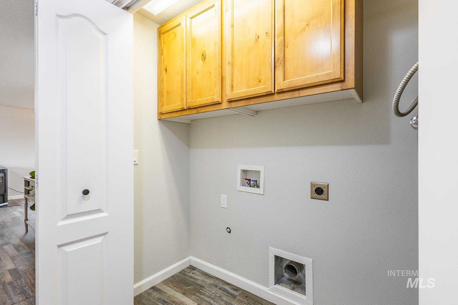 Laundry area with dark wood-type flooring, electric dryer hookup, washer hookup, and cabinet space