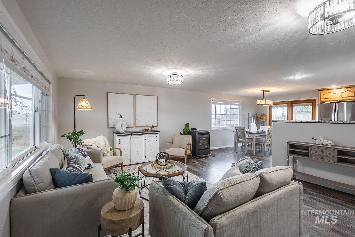 Living area with a wood stove, dark wood-style flooring, and a textured ceiling