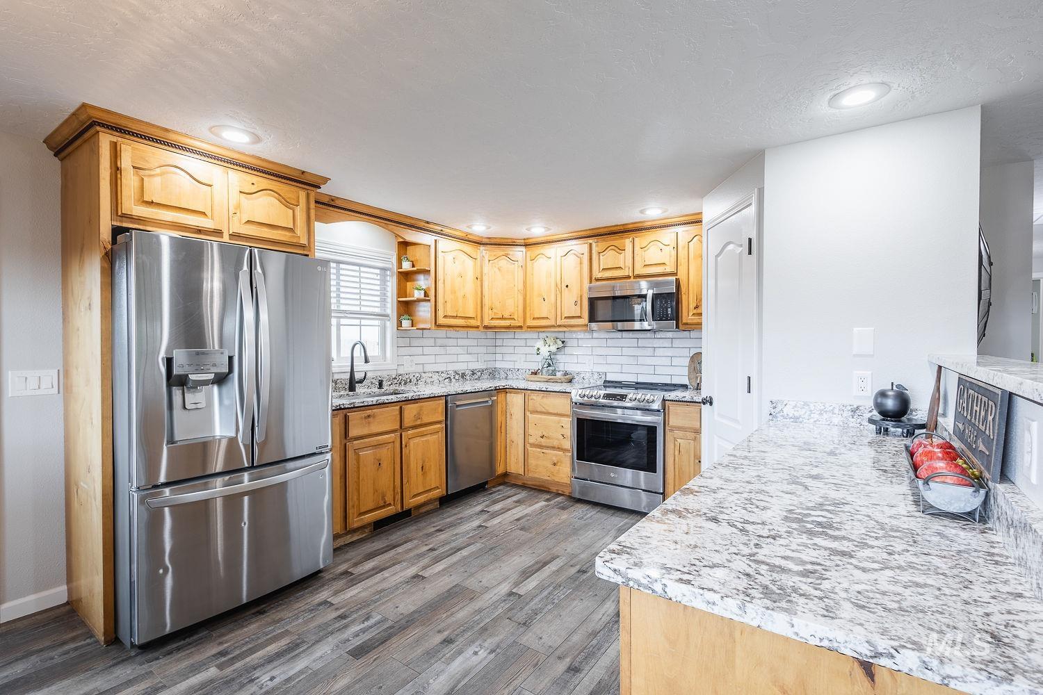 Kitchen featuring light stone counters, appliances with stainless steel finishes, tasteful backsplash, open shelves, and dark wood finished floors