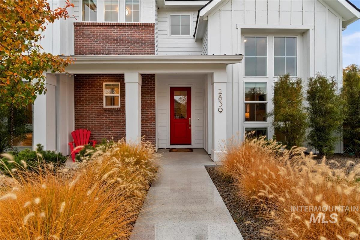View of exterior entry featuring board and batten siding, a porch, and brick siding