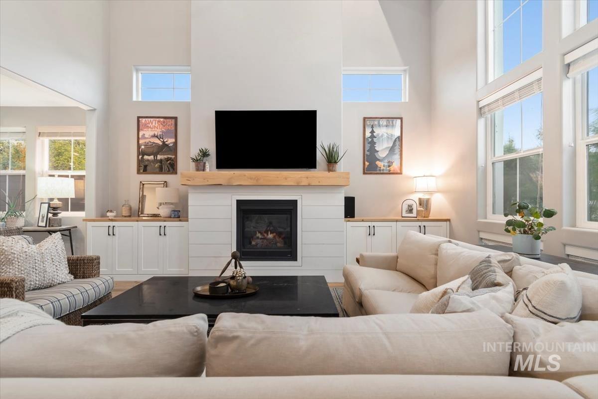 Living area featuring a high ceiling, a glass covered fireplace, and plenty of natural light