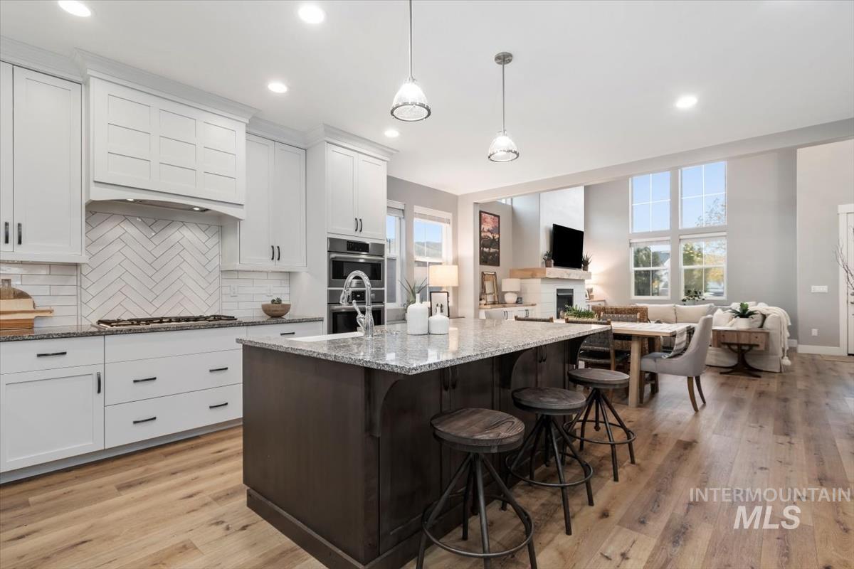 Kitchen featuring white cabinetry, dark brown cabinetry, dark stone counters, pendant lighting, and a breakfast bar