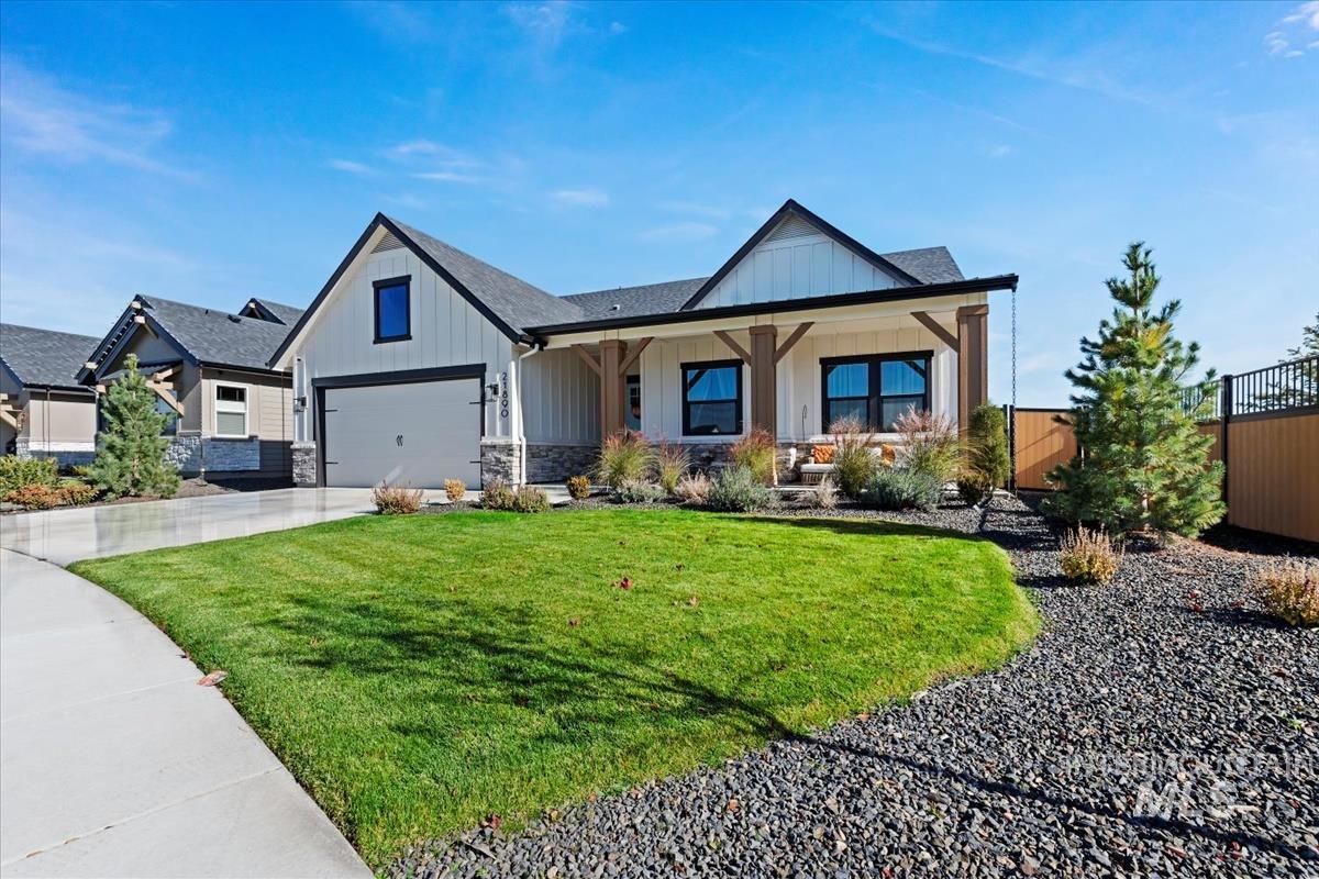 Modern inspired farmhouse featuring board and batten siding, a porch, driveway, stone siding, and a garage