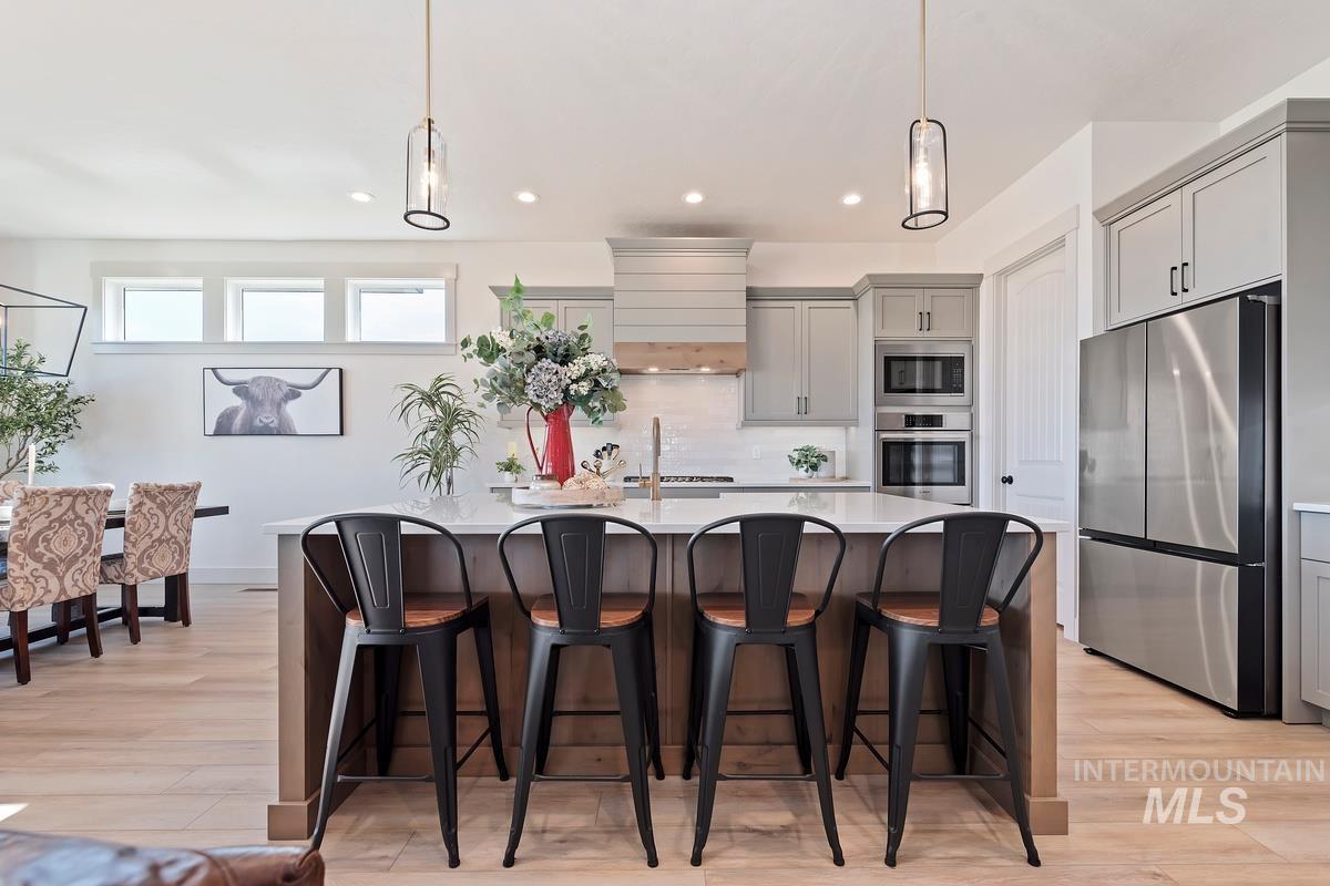 Kitchen featuring appliances with stainless steel finishes, gray cabinetry, backsplash, hanging light fixtures, and recessed lighting