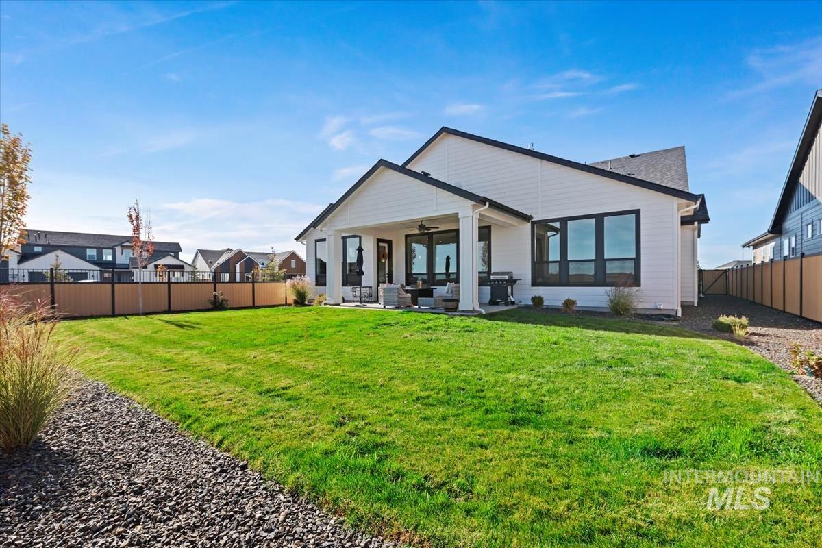 Back of house with ceiling fan, a fenced backyard, a patio, and outdoor lounge area