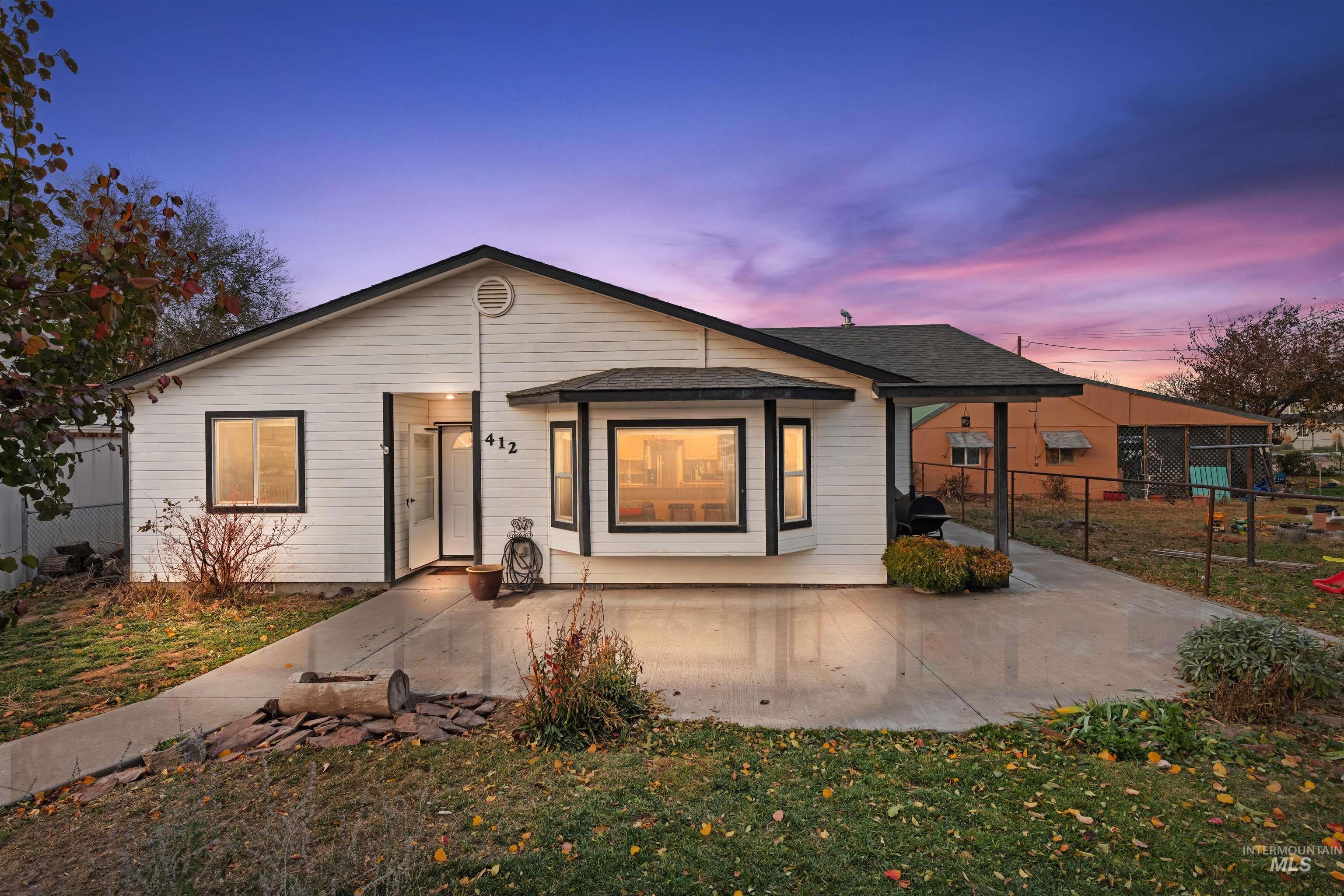 View of front facade with a shingled roof and a patio
