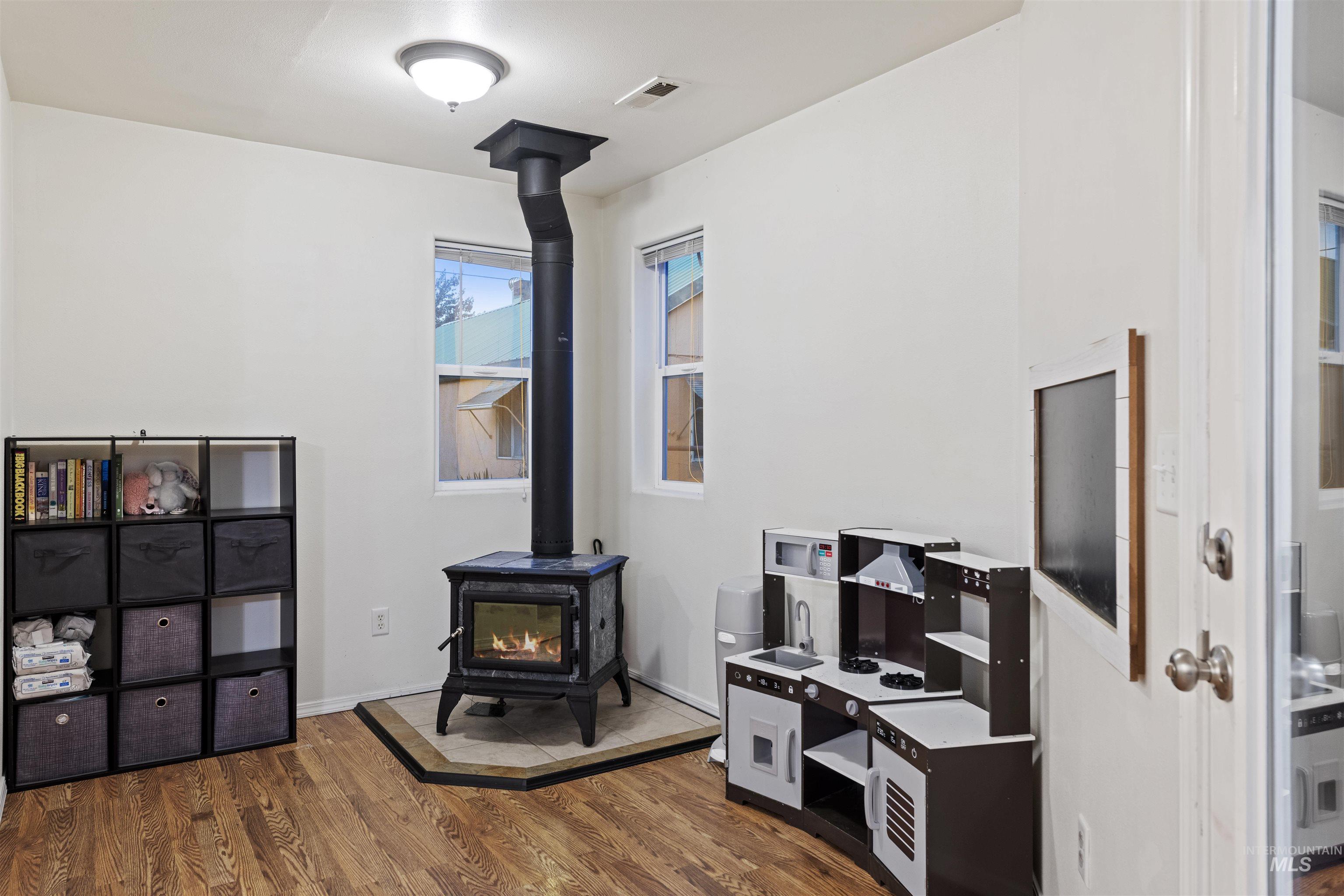 Home office featuring a wood stove and dark wood finished floors