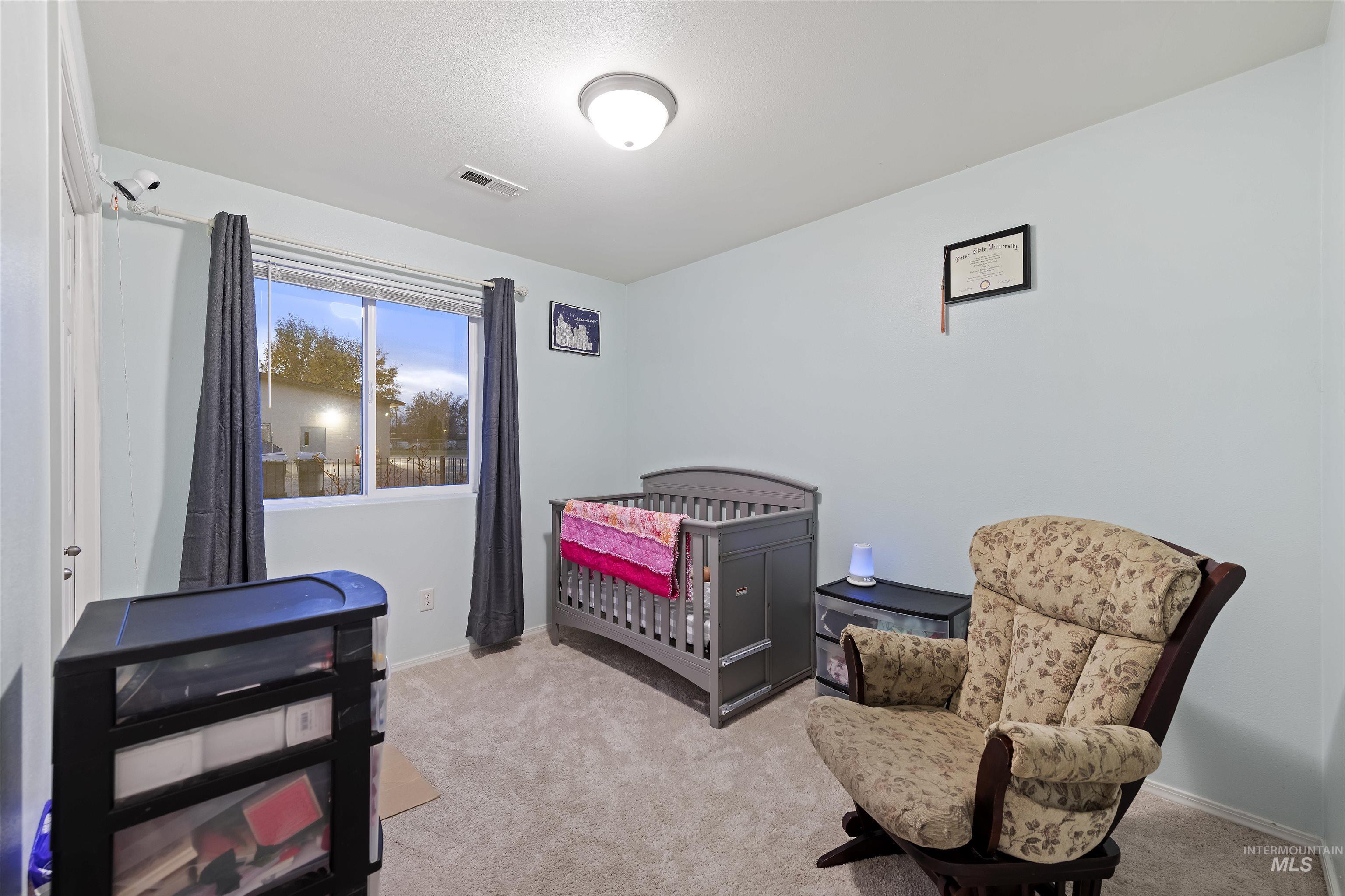 Bedroom featuring a crib and light colored carpet