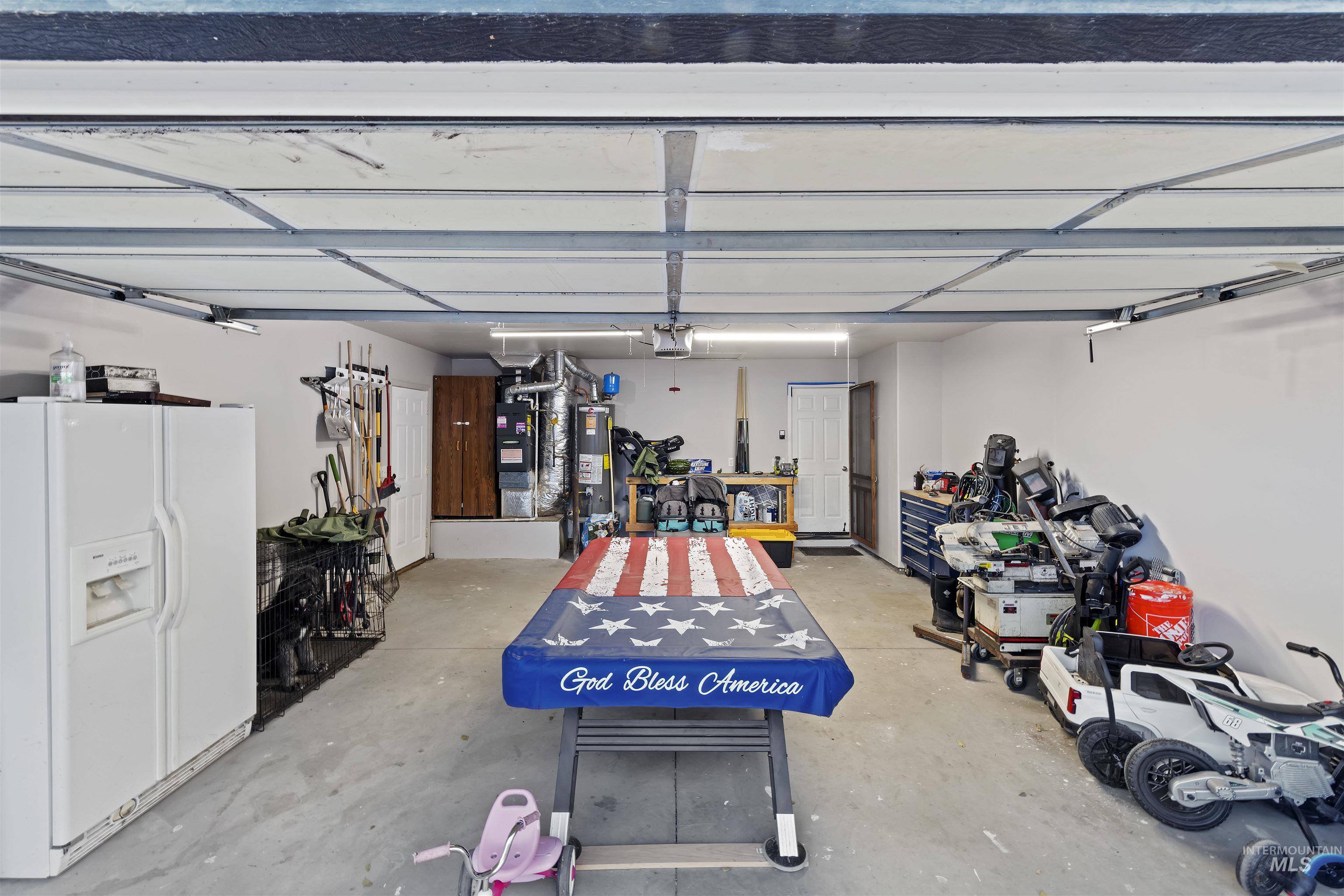 Garage with white refrigerator with ice dispenser and gas water heater