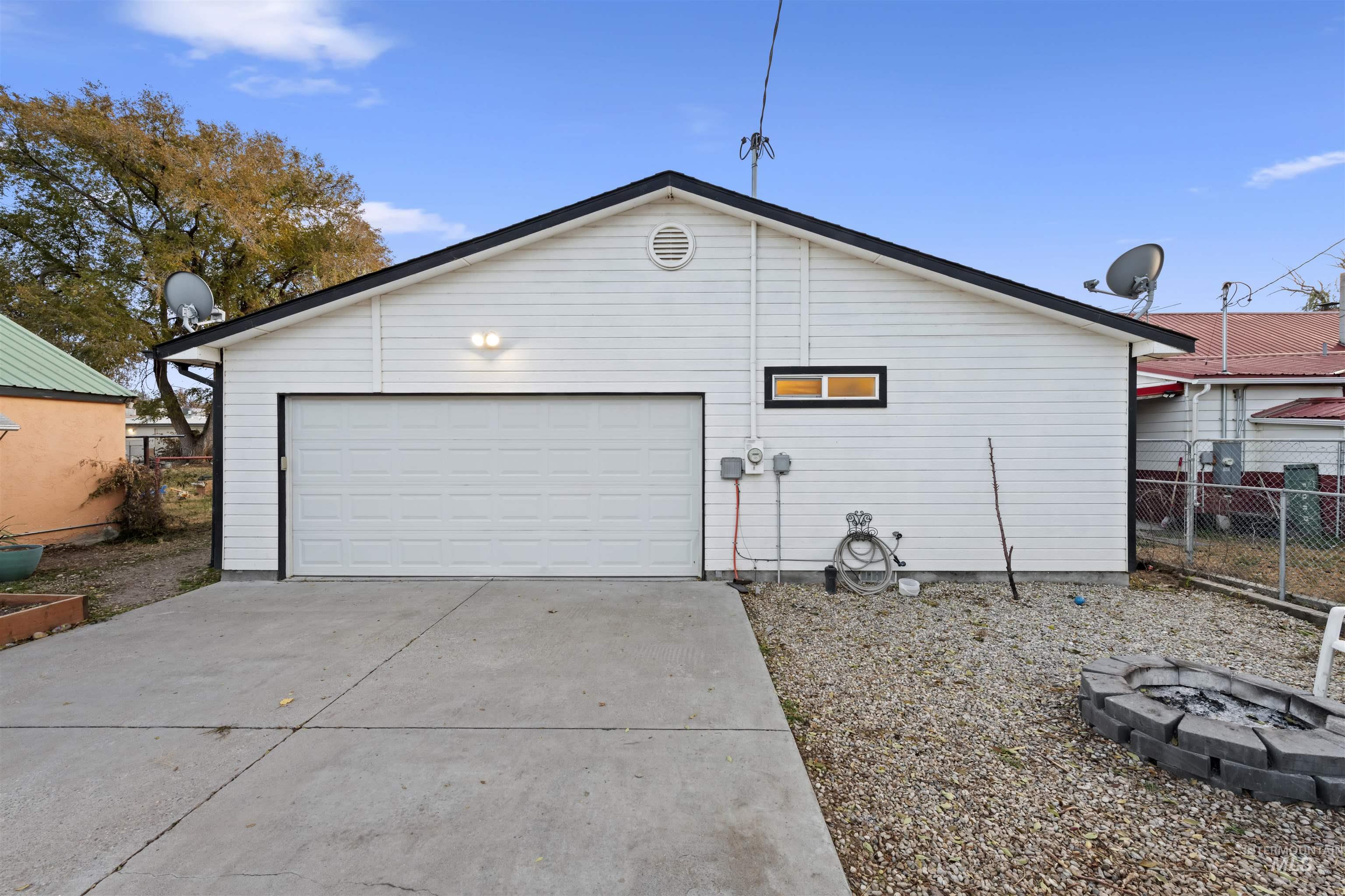 View of property exterior featuring driveway, a garage, and an outdoor fire pit