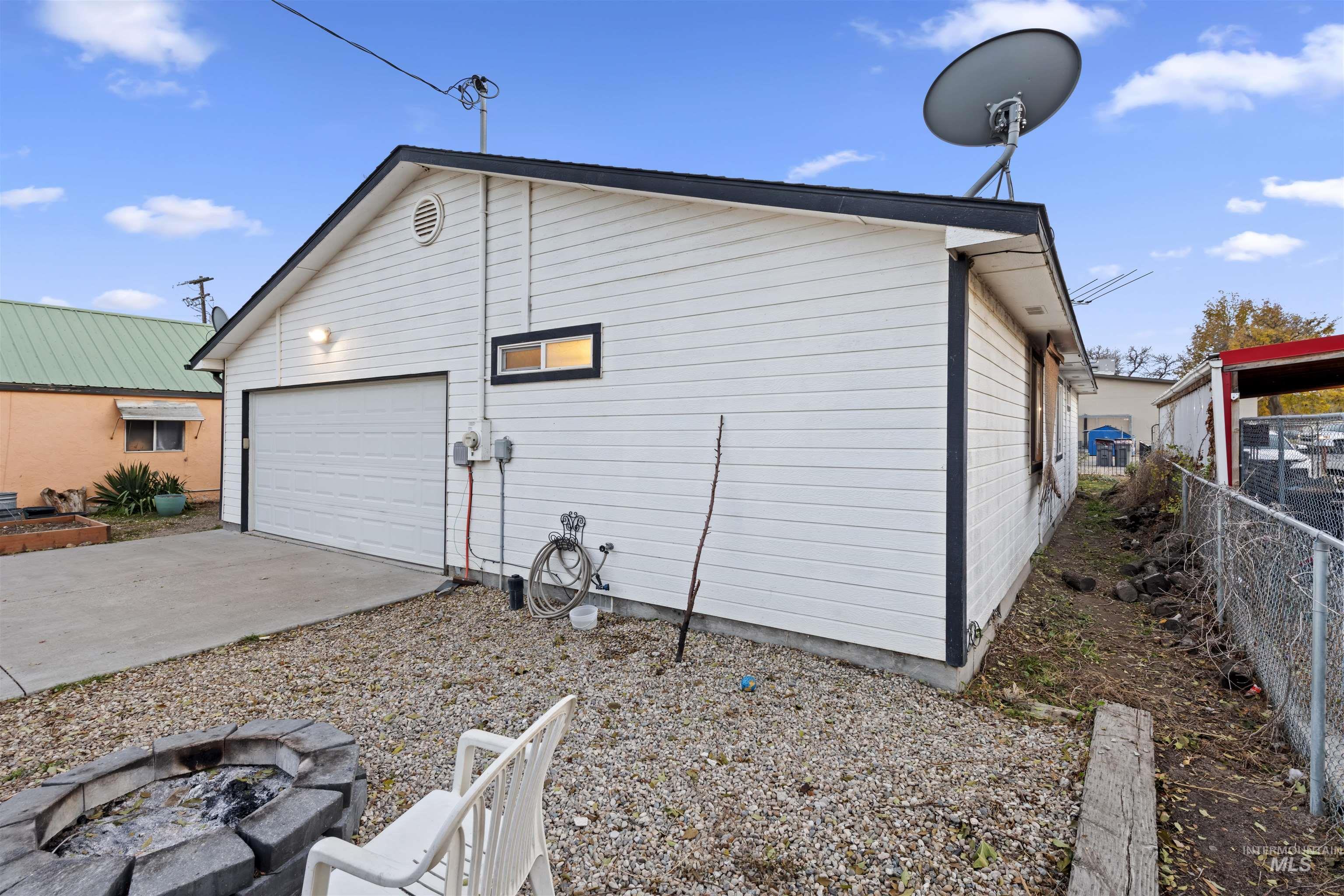 View of side of property featuring a fire pit, a garage, concrete driveway, and a patio area