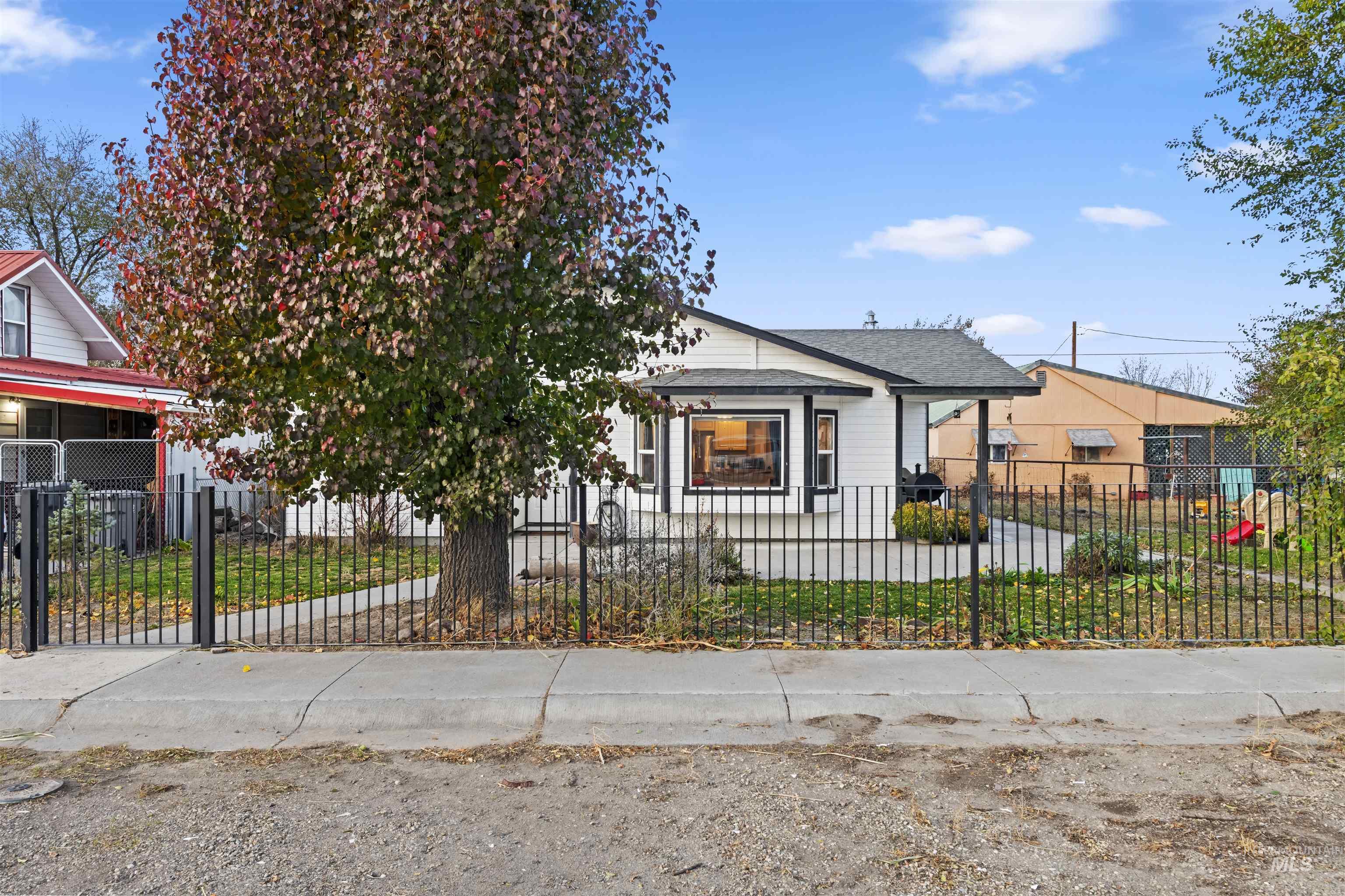 Bungalow-style house with a fenced front yard, roof with shingles, and covered porch