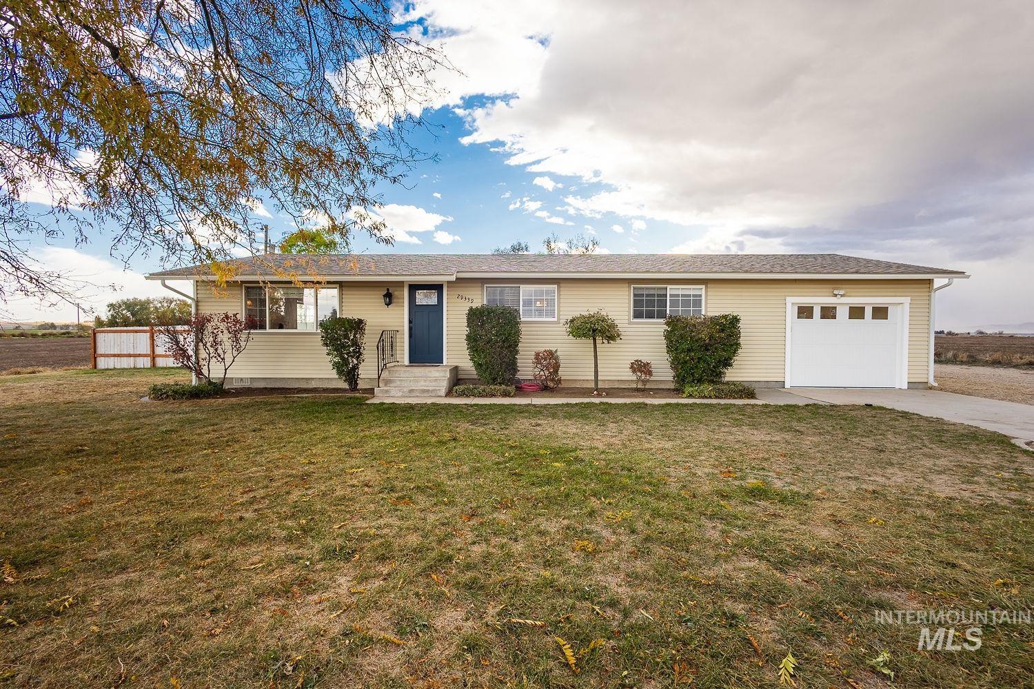 Ranch-style house featuring a front yard, a garage, and driveway