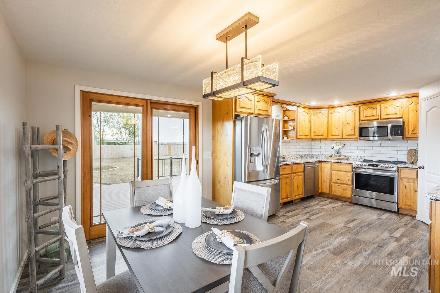 Kitchen featuring open shelves, backsplash, stainless steel appliances, light wood-style floors, and light stone countertops