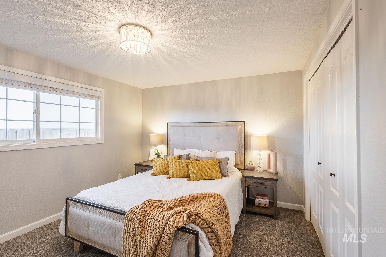Bedroom featuring a textured ceiling, dark carpet, and a closet