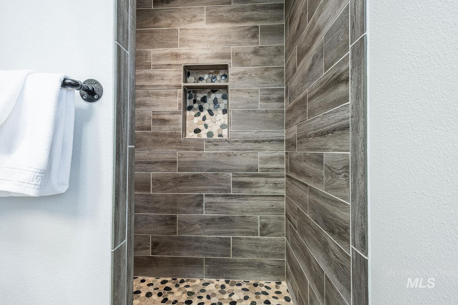Bathroom featuring a textured wall and a tile shower