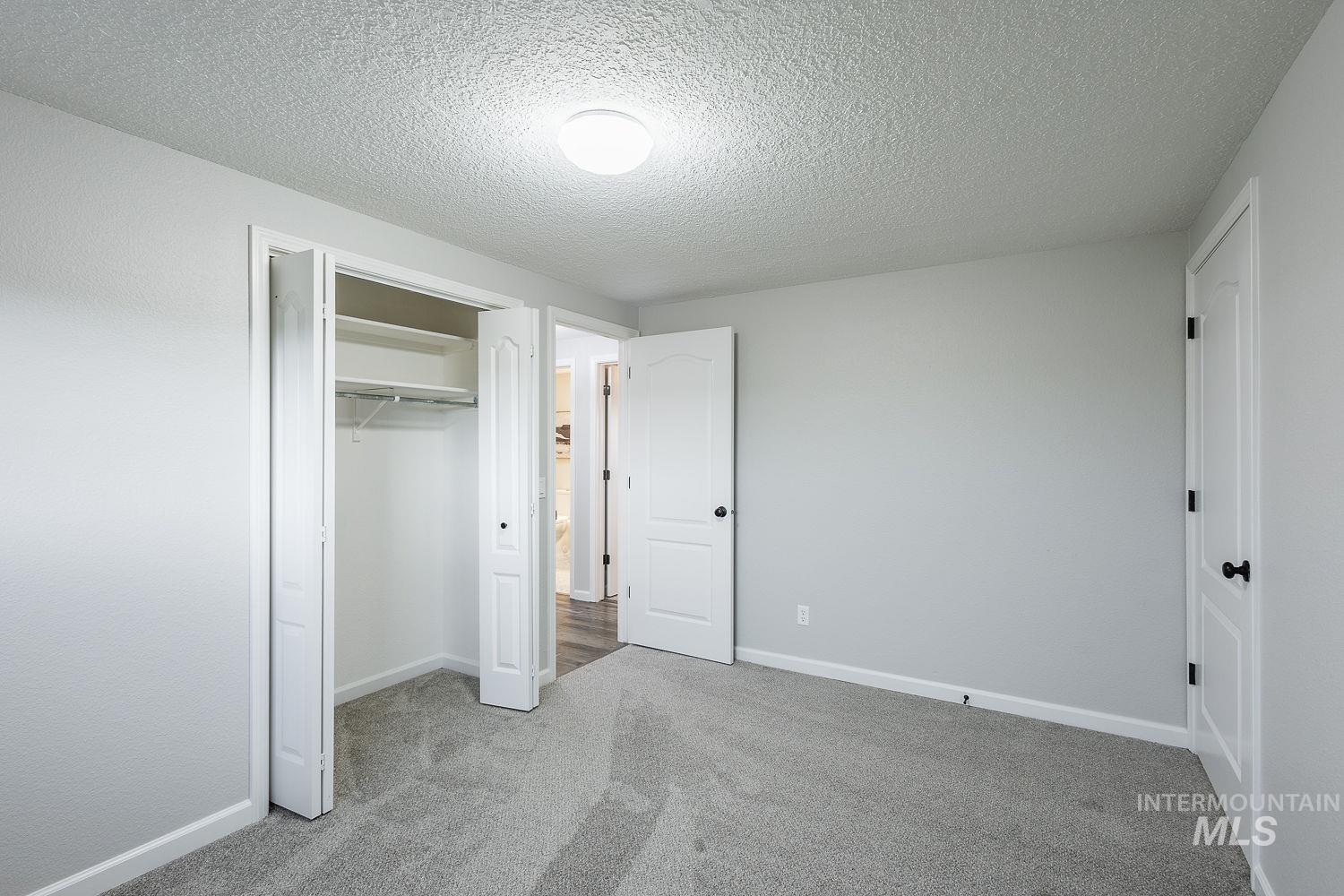 Unfurnished bedroom with light carpet, a textured ceiling, and a closet