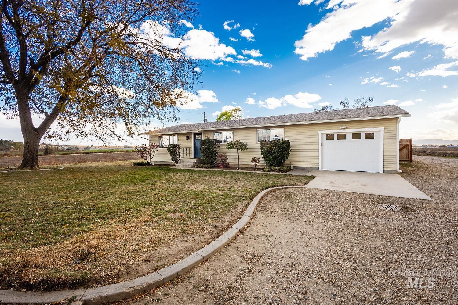 Ranch-style home featuring driveway, a garage, and a front lawn