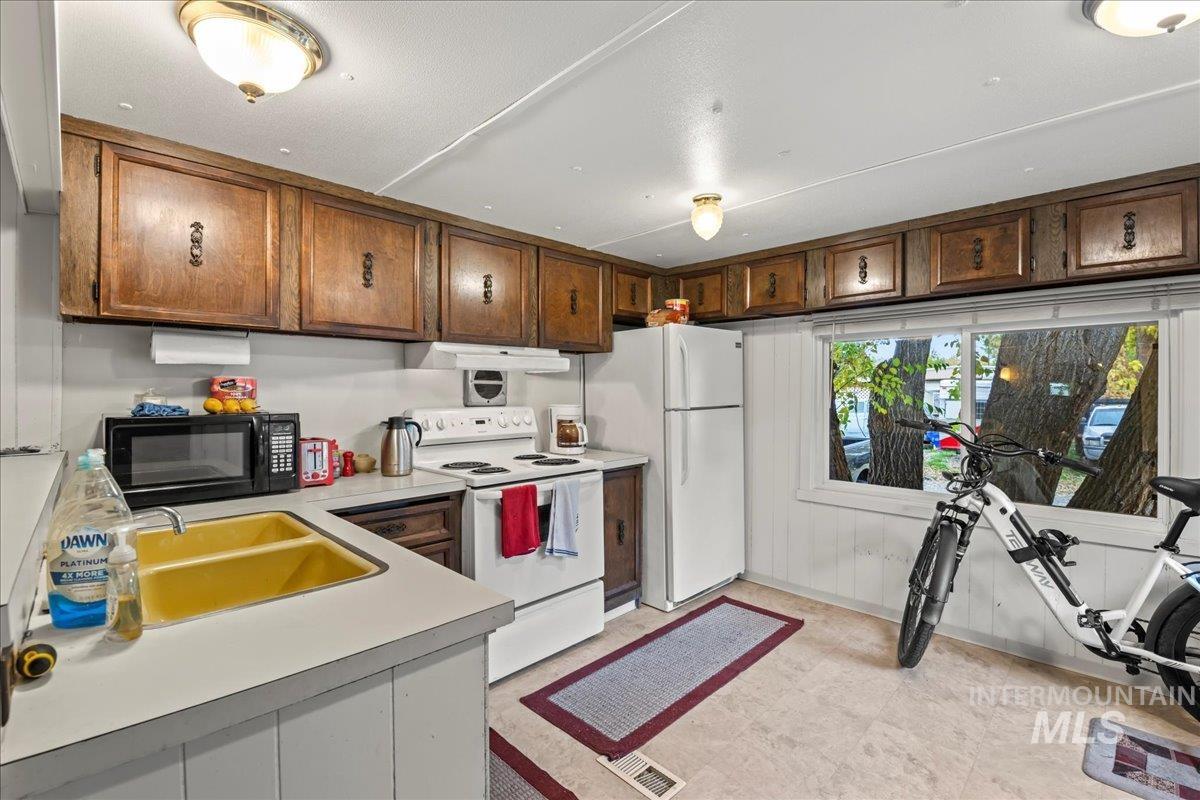 Kitchen with white appliances, light countertops, and under cabinet range hood