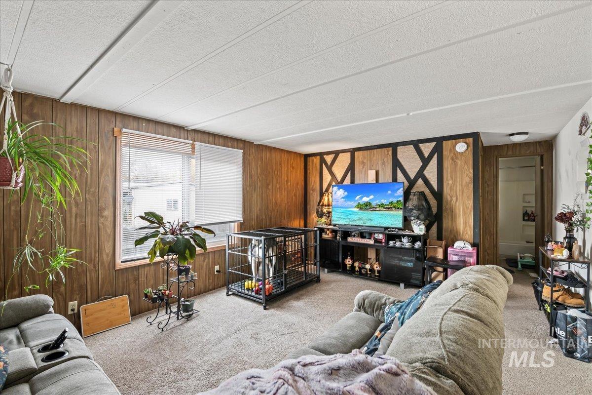 Living area with wood walls, carpet, and a textured ceiling