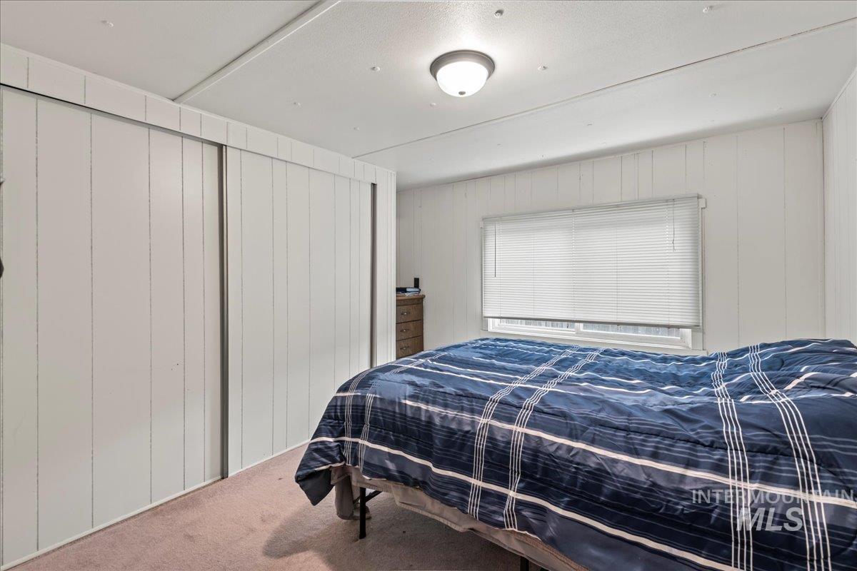 Carpeted bedroom featuring wood walls