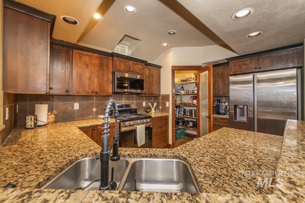 Kitchen featuring stainless steel appliances, light stone countertops, recessed lighting, backsplash, and a textured ceiling