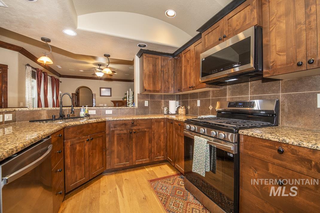 Kitchen with appliances with stainless steel finishes, hanging light fixtures, light stone counters, recessed lighting, and tasteful backsplash