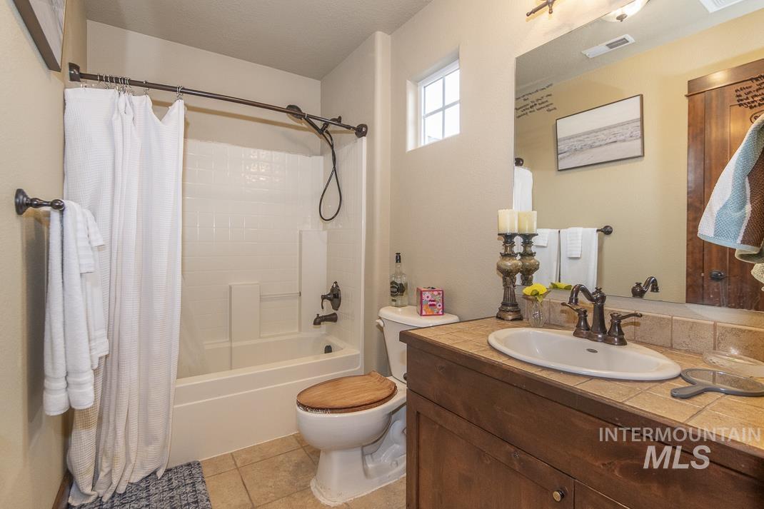 Bathroom with vanity, light tile patterned flooring, and shower / bath combination with curtain