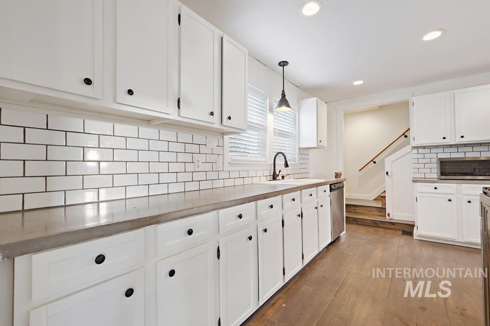 Kitchen with tasteful backsplash, hanging light fixtures, white cabinets, dark wood-style floors, and recessed lighting