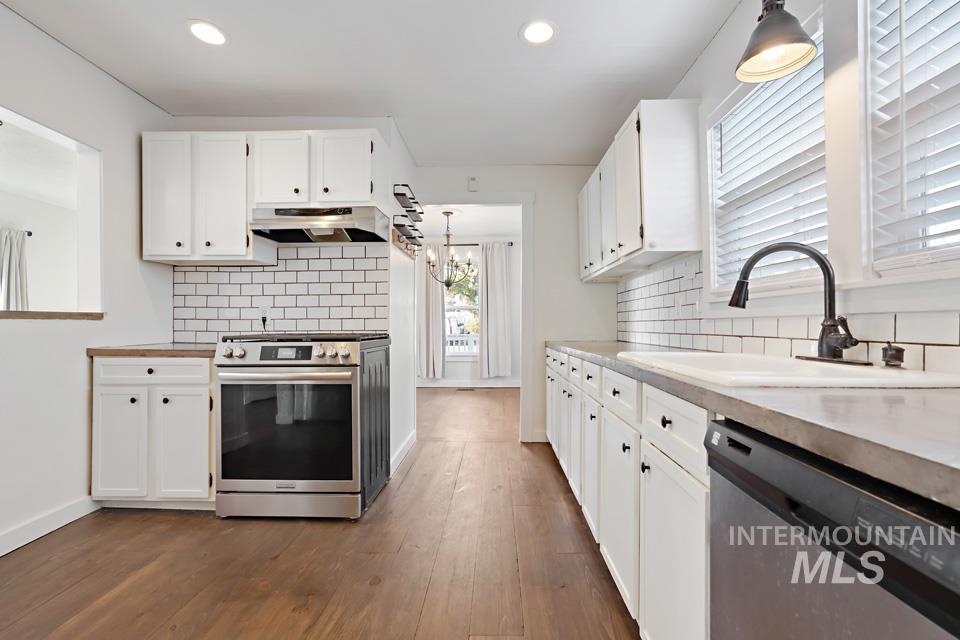 Kitchen featuring white cabinets, stainless steel appliances, decorative backsplash, recessed lighting, and dark wood-style flooring