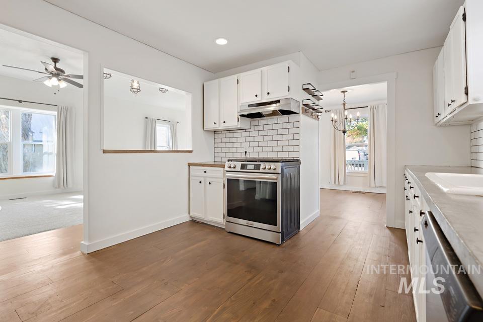 Kitchen featuring white cabinets, appliances with stainless steel finishes, backsplash, dark wood finished floors, and recessed lighting