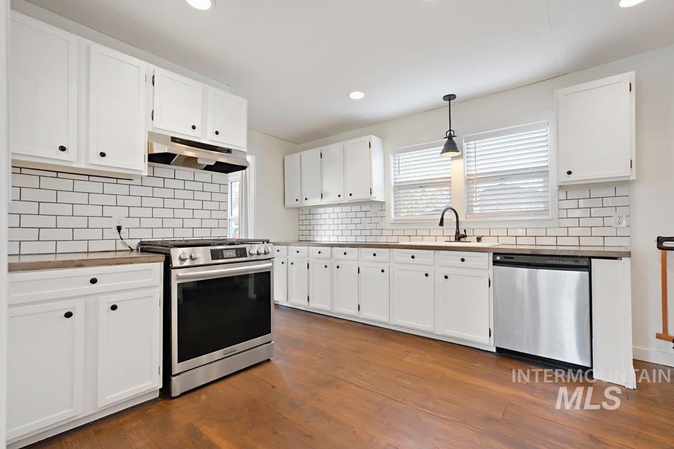 Kitchen featuring stainless steel appliances, white cabinets, hanging light fixtures, and recessed lighting