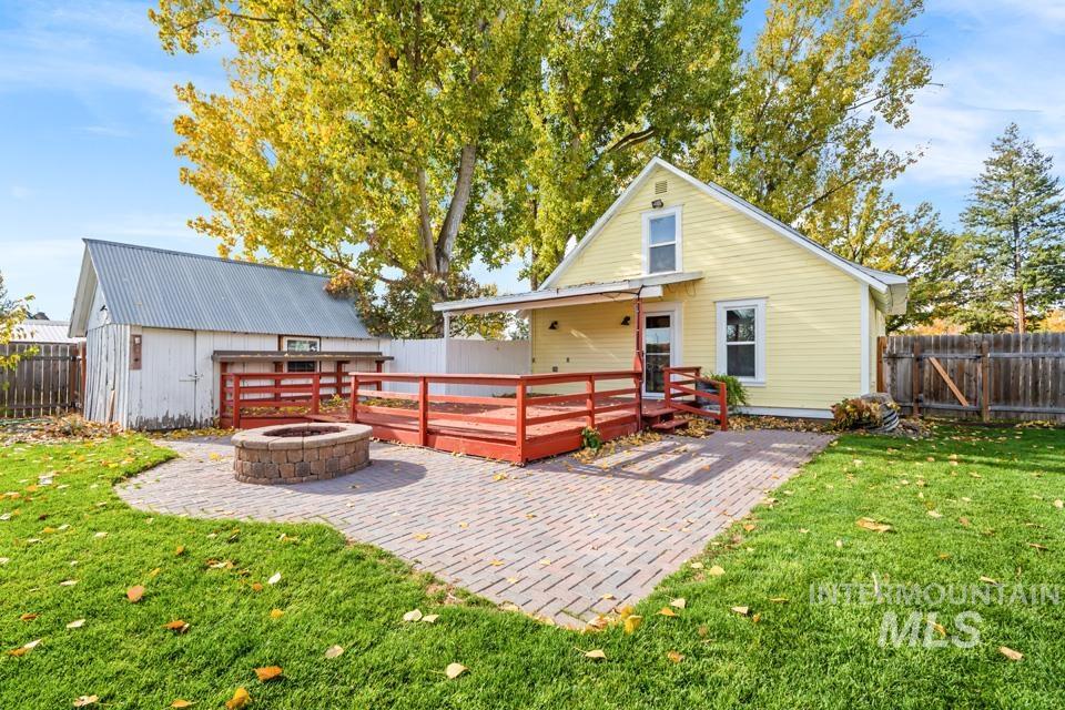 Rear view of property with an outdoor fire pit, a fenced backyard, a deck, and a patio