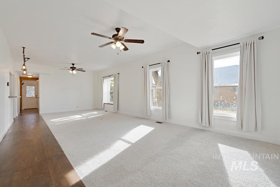 Unfurnished living room with ceiling fan, carpet flooring, and hardwood / wood-style flooring