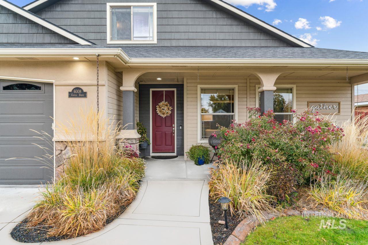 Doorway to property with covered porch, a shingled roof, and a garage