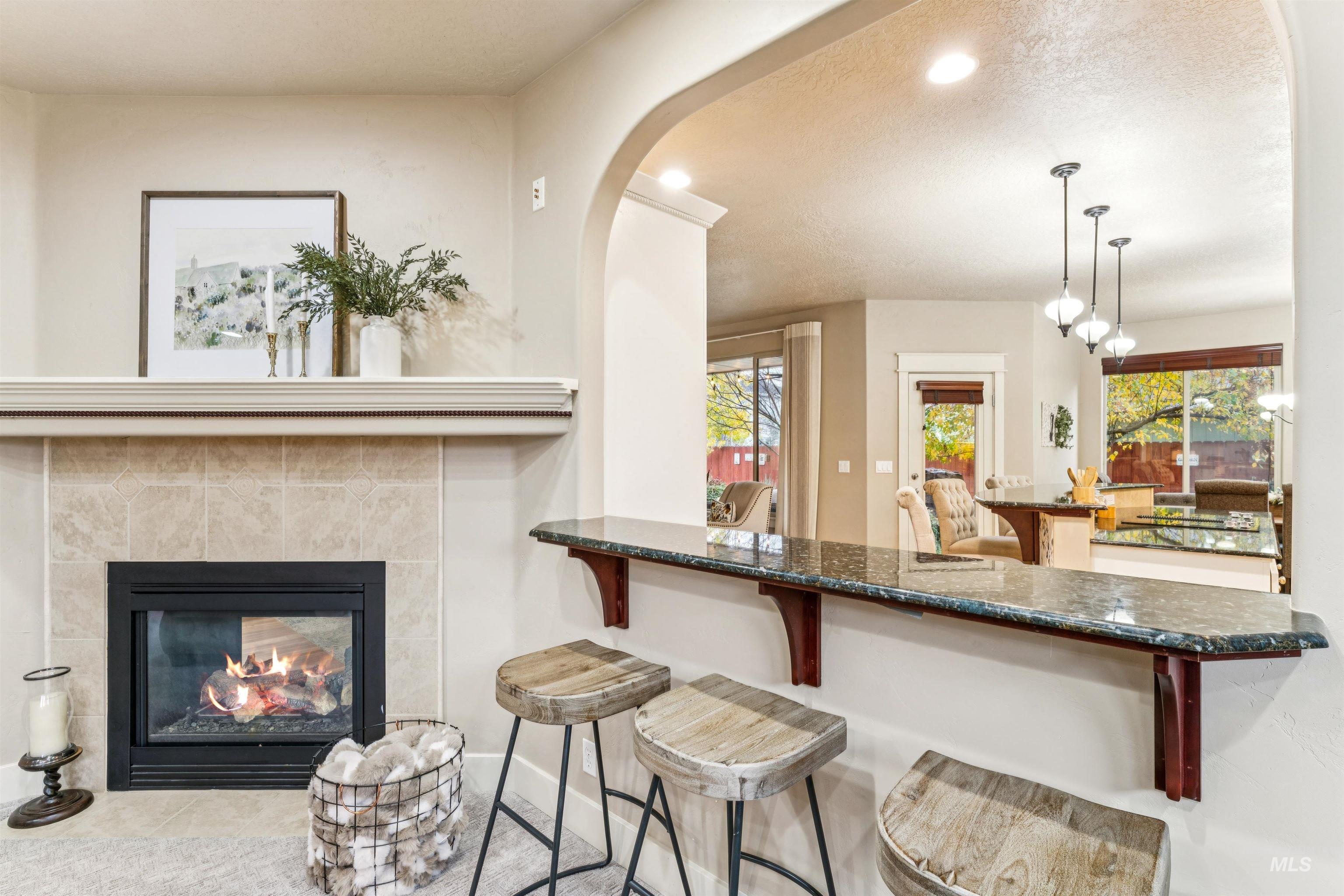 Kitchen with recessed lighting, a fireplace, pendant lighting, a textured ceiling, and dark stone countertops