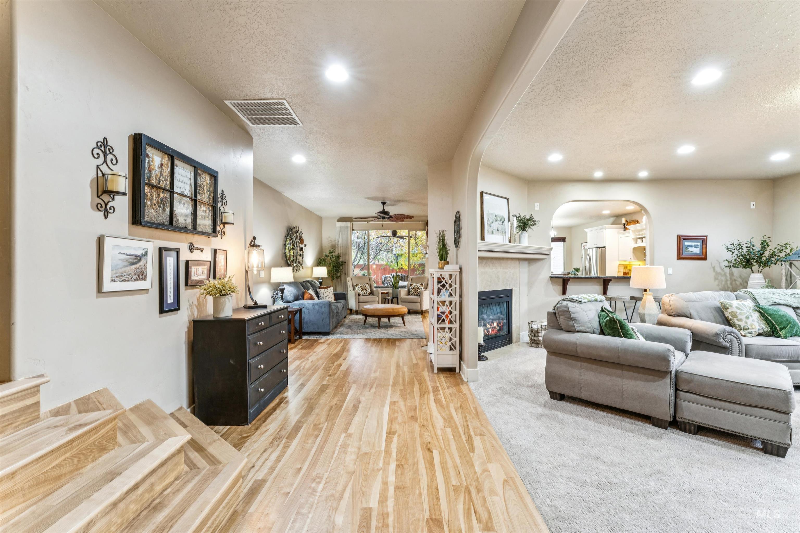 Living room with a textured ceiling, light wood-style floors, recessed lighting, arched walkways, and ceiling fan