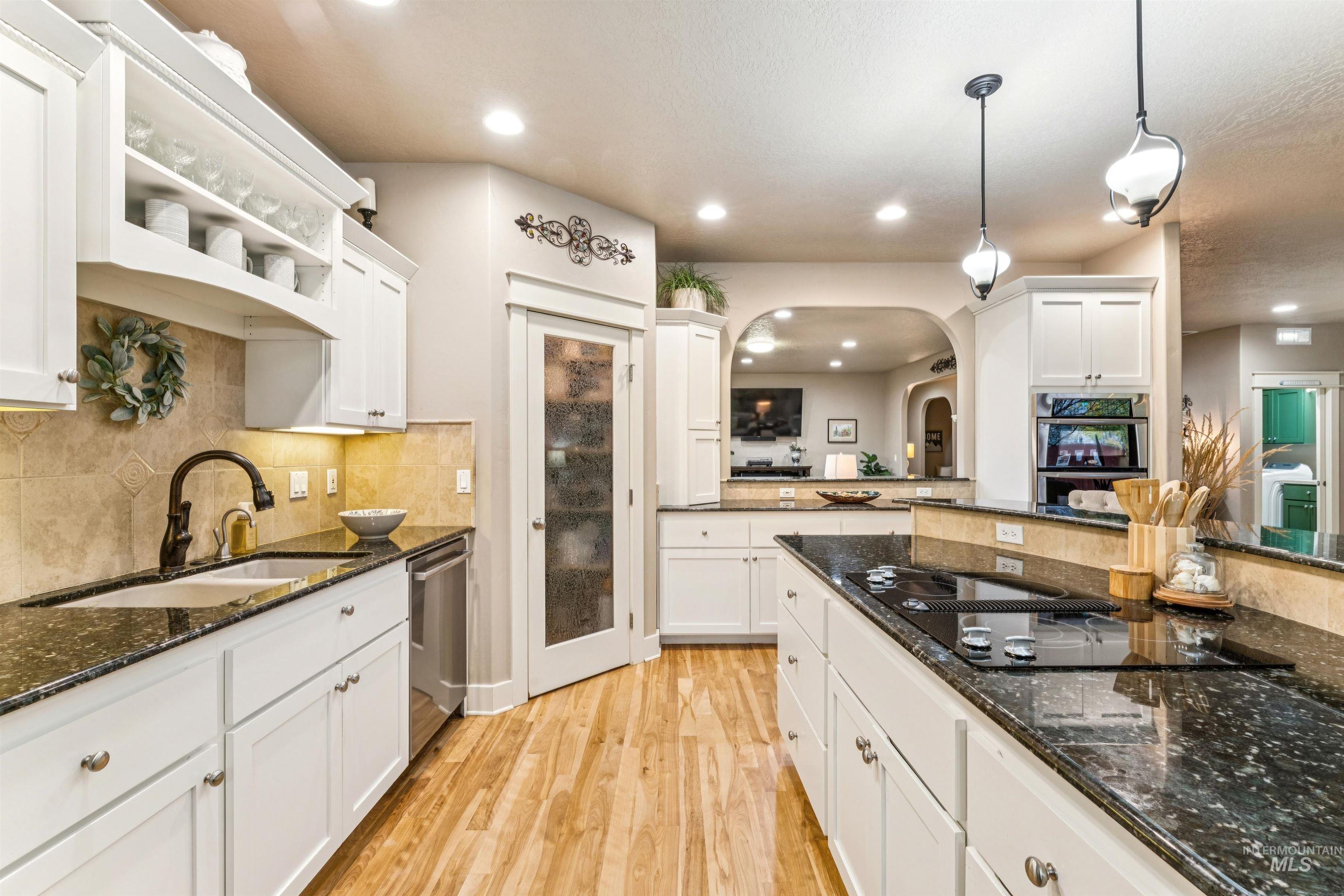 Kitchen featuring dark stone countertops, white cabinetry, pendant lighting, light wood finished floors, and recessed lighting