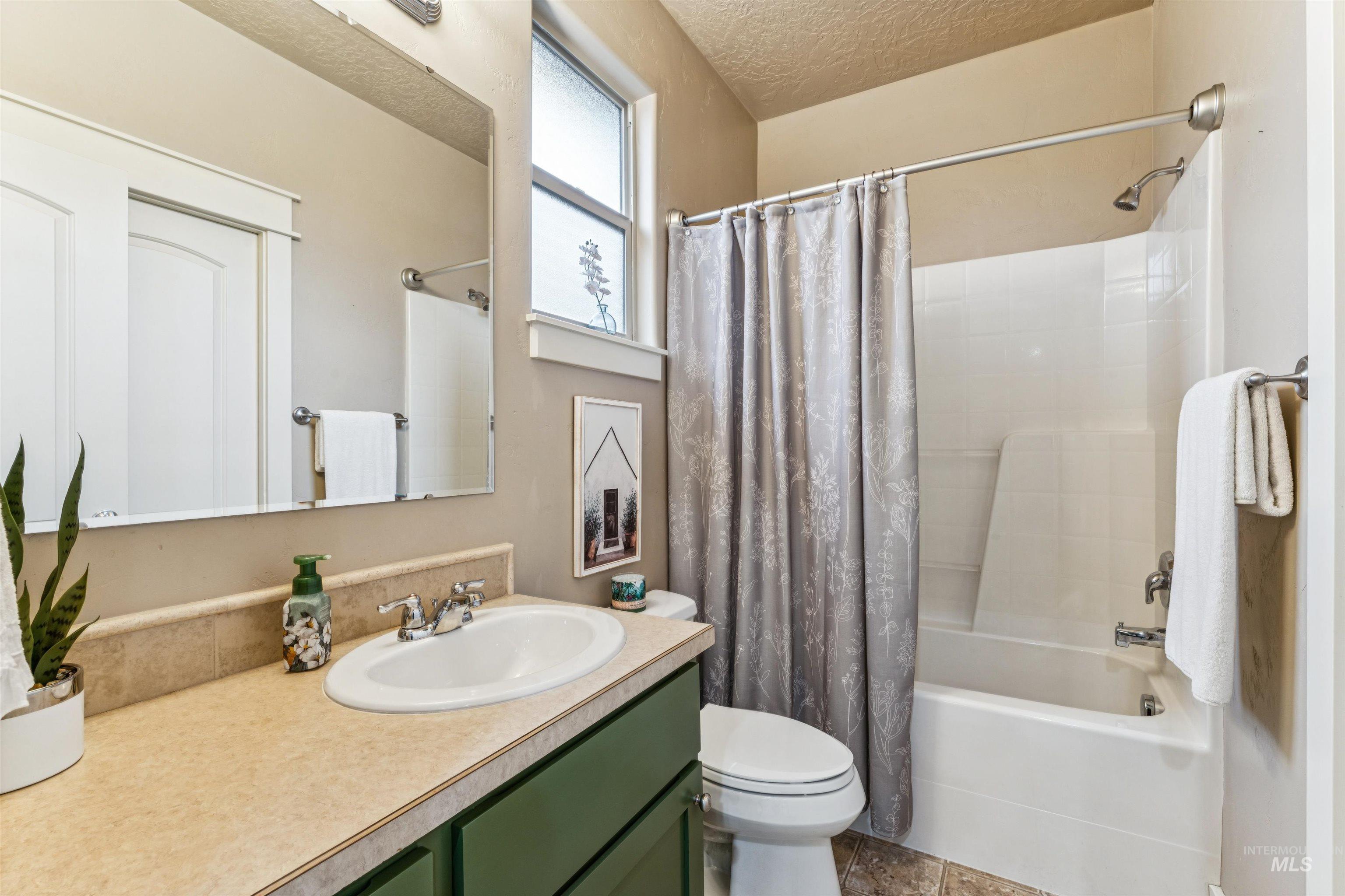 Bathroom with shower / tub combo with curtain, a textured ceiling, vanity, and tile patterned floors