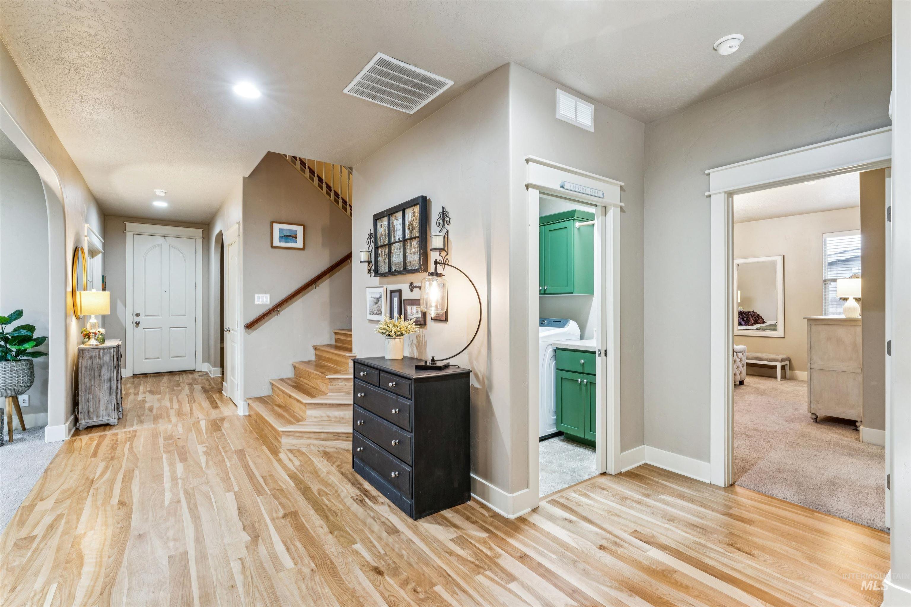 Corridor featuring light wood-style floors, washer / clothes dryer, stairway, and recessed lighting