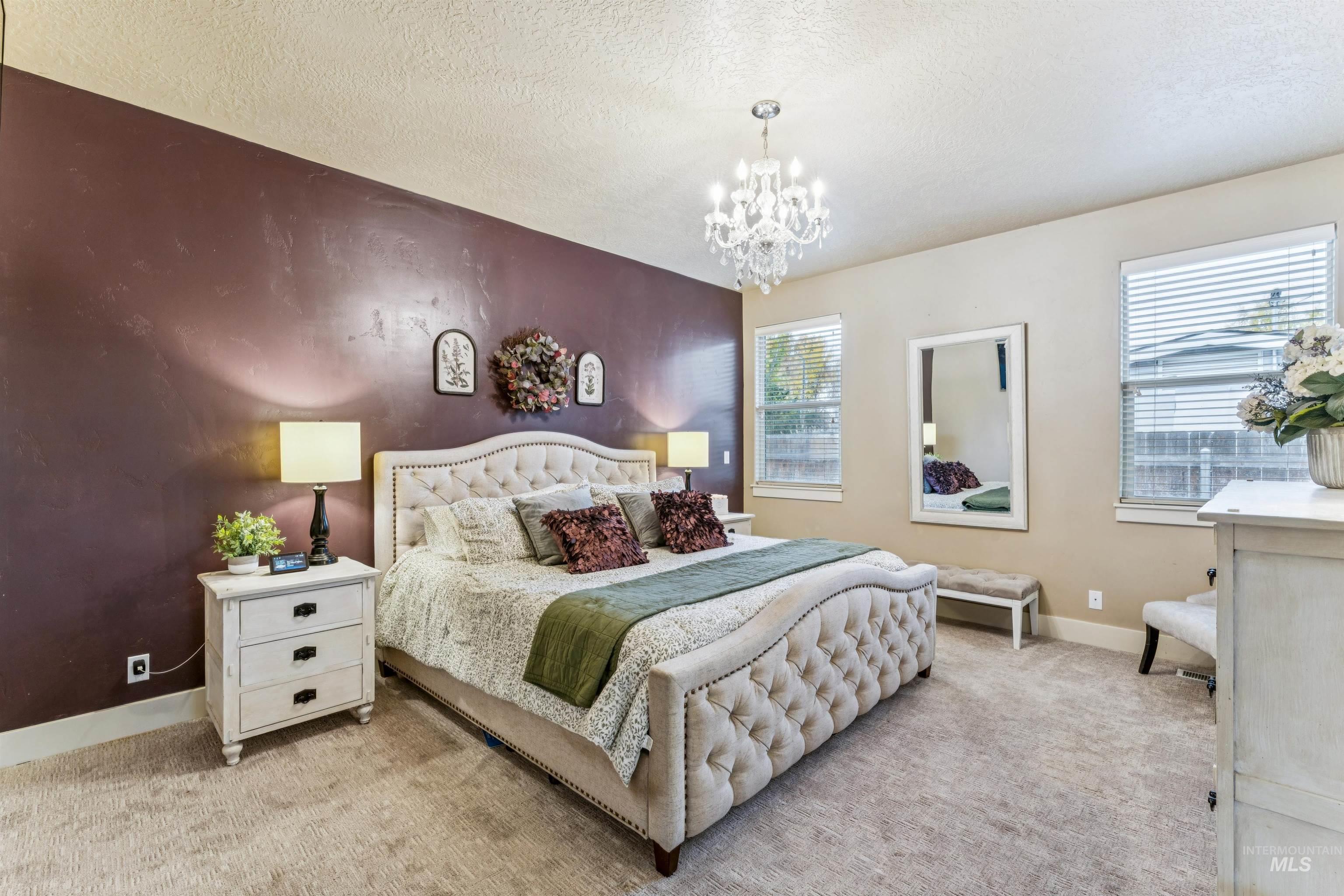 Carpeted bedroom featuring a textured ceiling and a chandelier