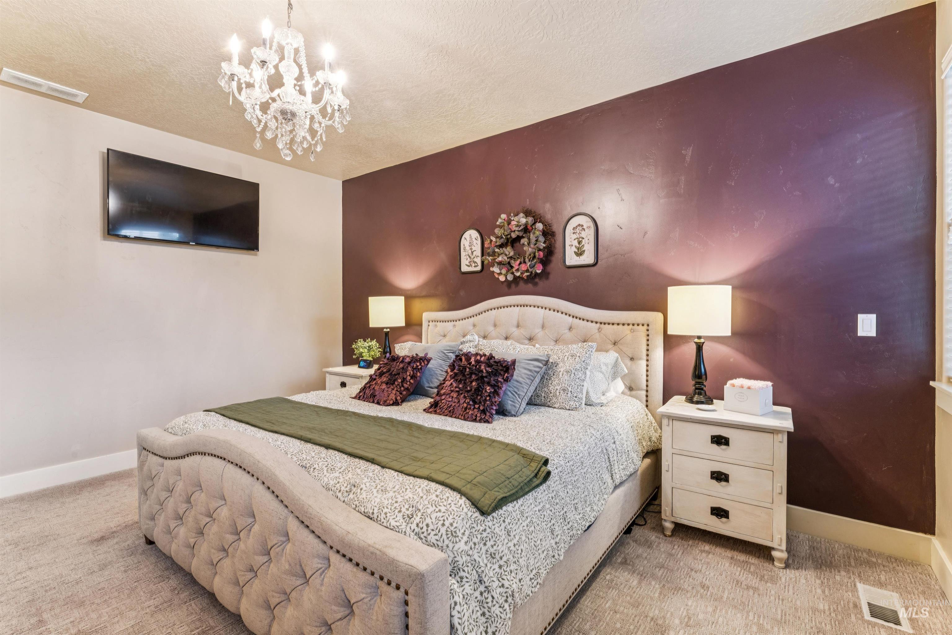 Carpeted bedroom featuring a chandelier and a textured ceiling