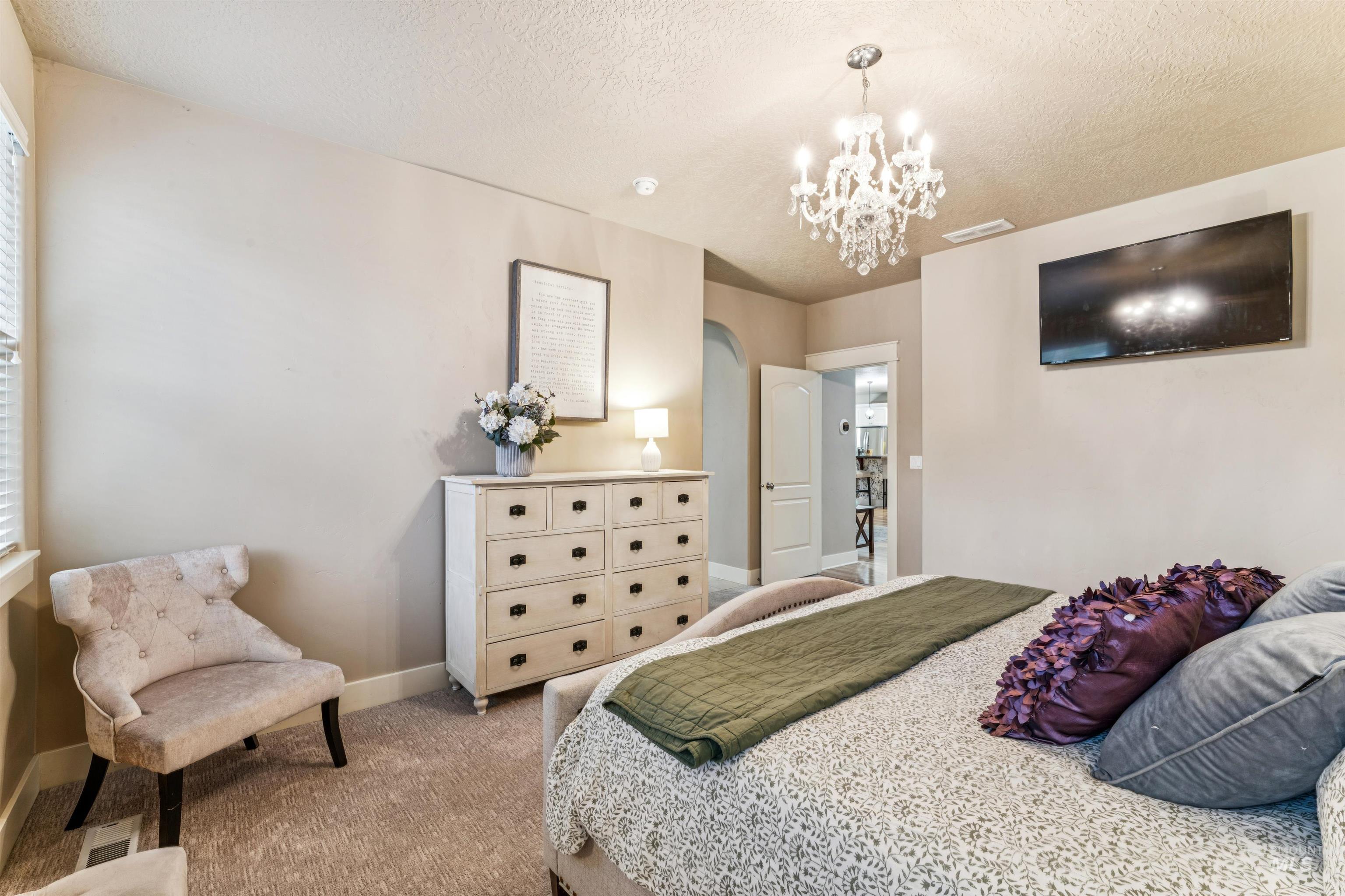 Bedroom with carpet flooring, a textured ceiling, a chandelier, and arched walkways