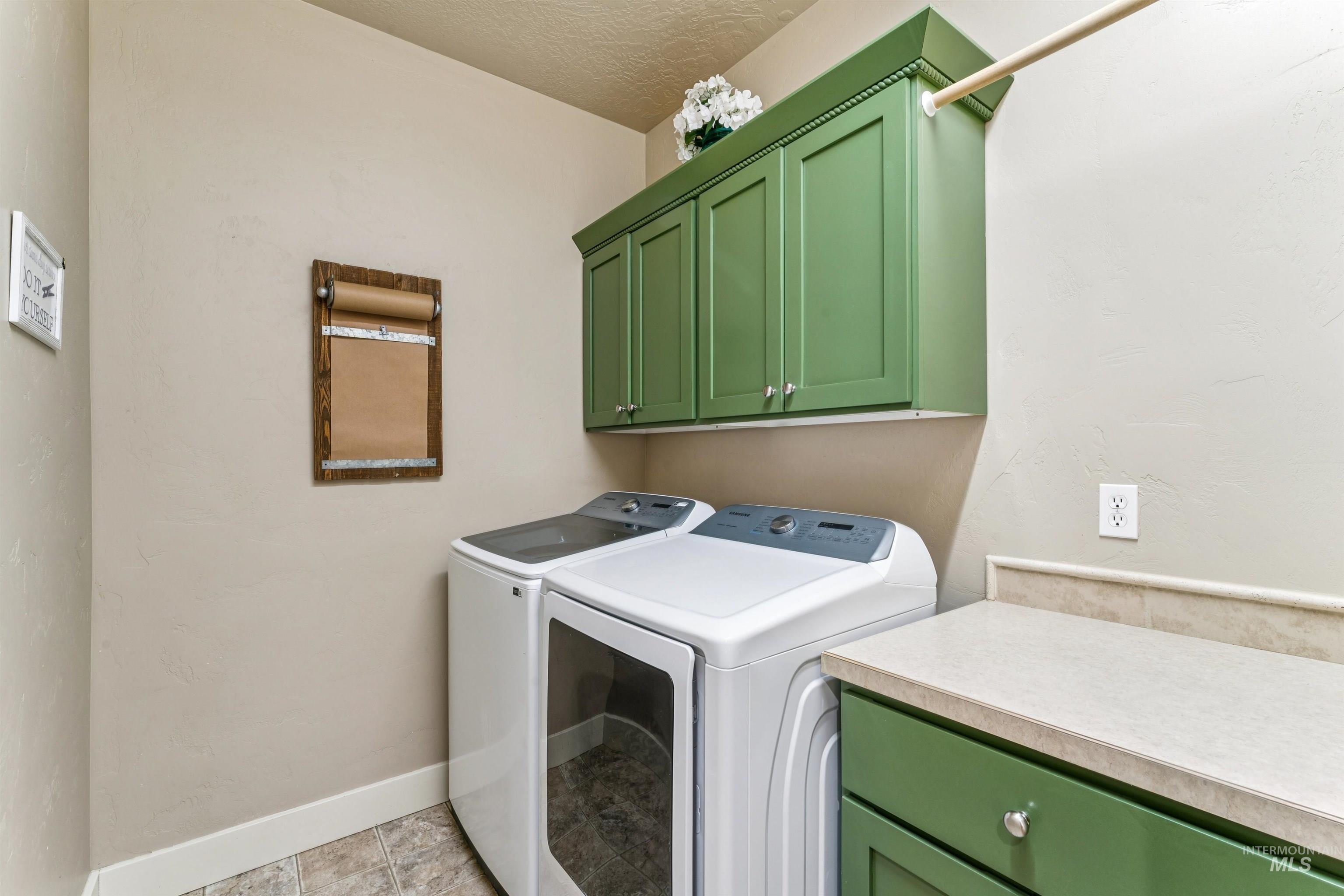 Laundry area featuring cabinet space, independent washer and dryer, a textured ceiling, and light tile patterned floors